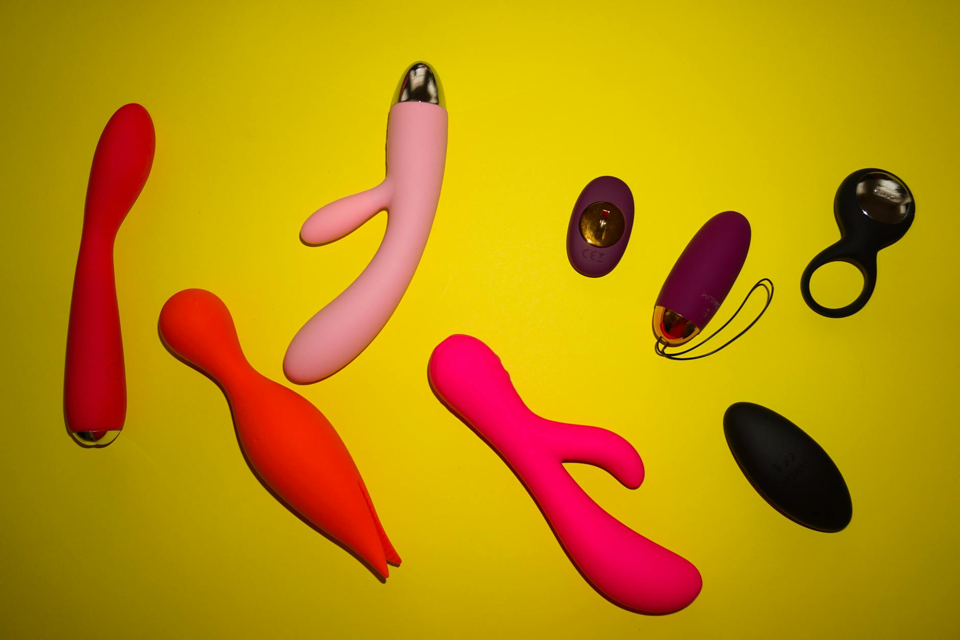 Pink vibrator on purple background with candles and heart confetti for romantic intimacy